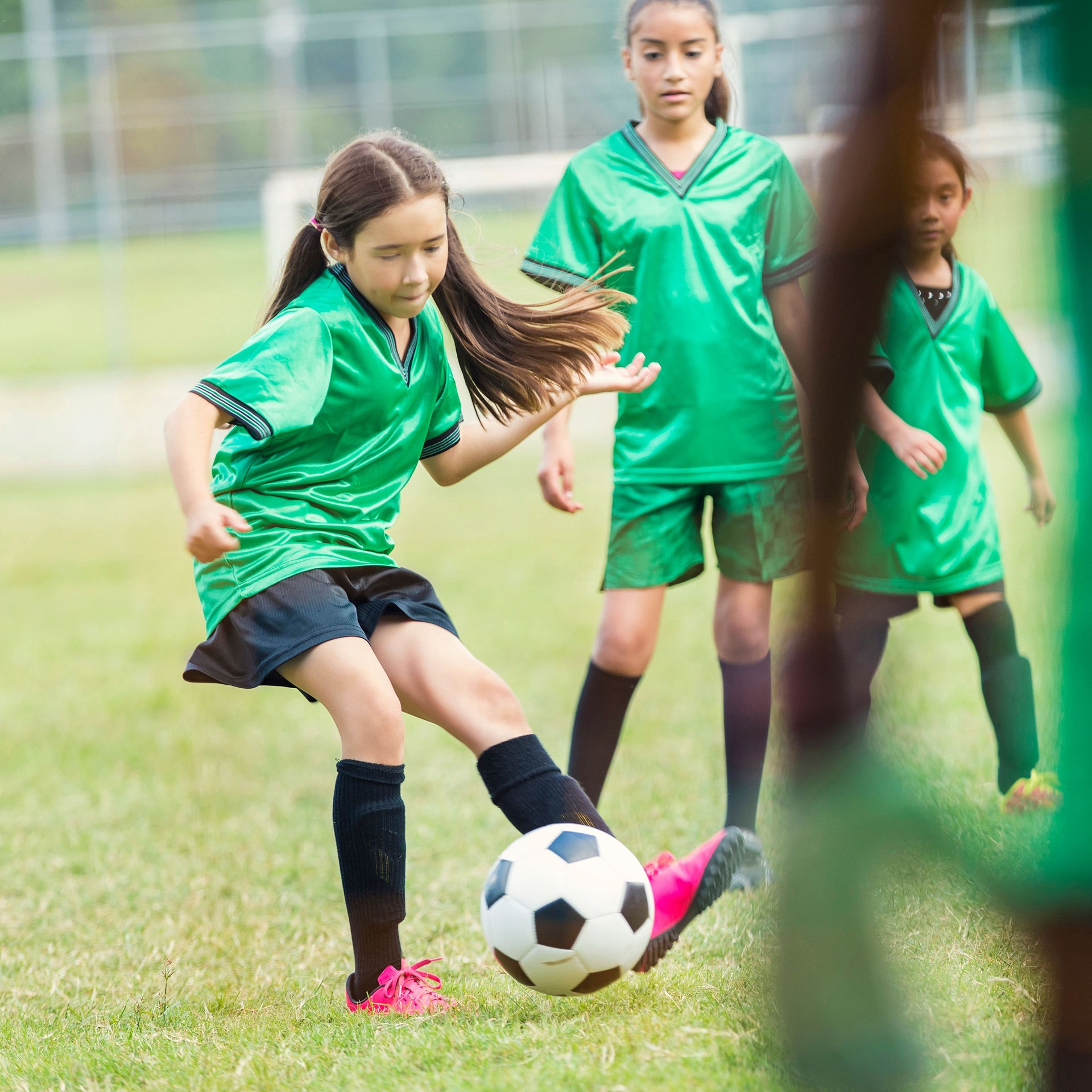 Hispanic female athlete kicks soccer ball during game